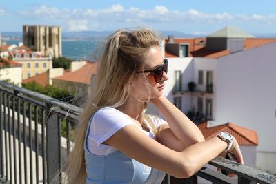 Side view of young woman wearing sunglasses on railing