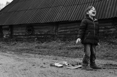 Boy with tied shoes on legs screaming while standing on field