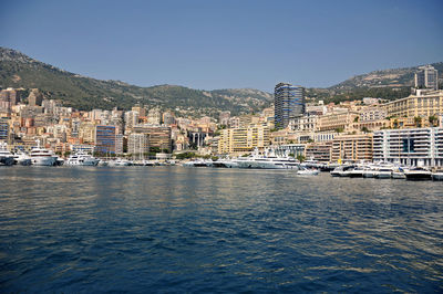 Buildings by sea against clear sky