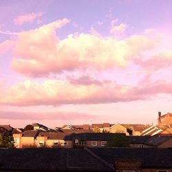 Houses against cloudy sky at sunset