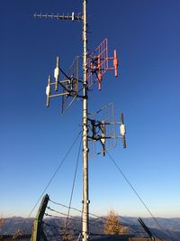 Low angle view of telephone pole against clear blue sky