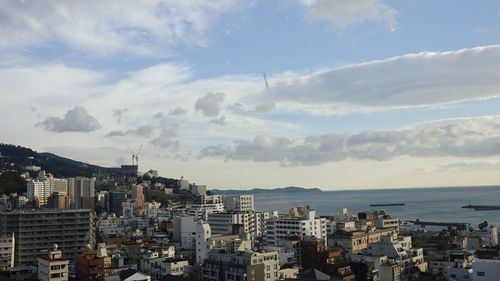 Aerial view of city by sea against sky