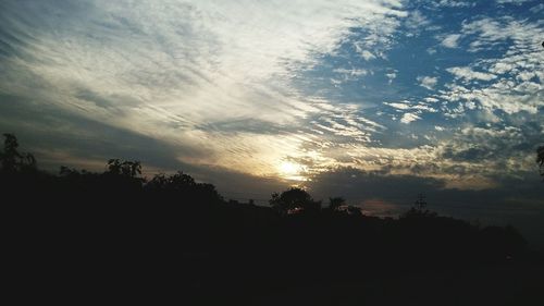 Silhouette of trees against cloudy sky