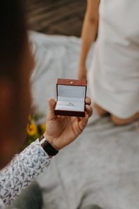 Cropped hand of man holding ring against woman