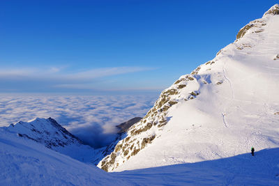 Scenic view of snowcapped mountains against blue sky