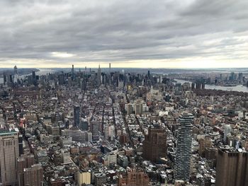 High angle view of city buildings against cloudy sky