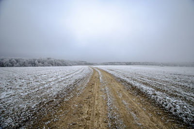 Snow covered land road against sky during winter