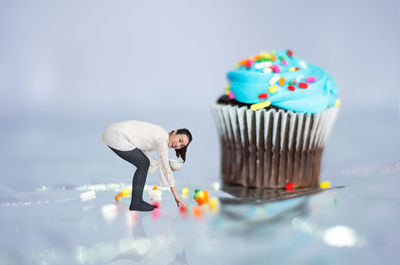 Portrait of young woman picking up sprinkles by large pancake table