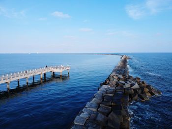 Wooden posts in sea against sky