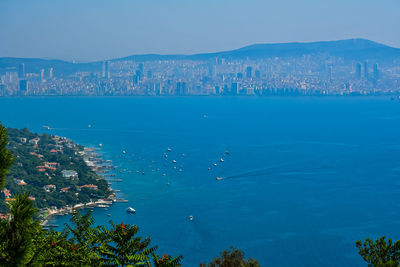 Sea by city buildings against blue sky