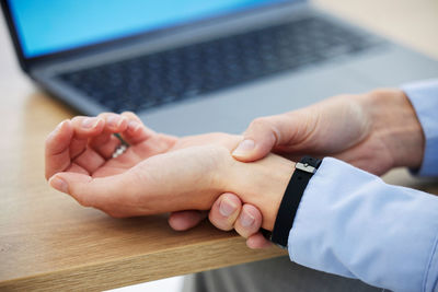 Cropped hands of man using laptop on table