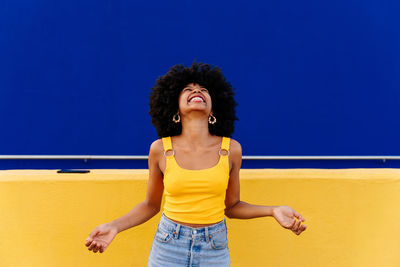 Portrait of young woman standing against blue sky