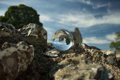 Close-up of crystal ball on rock against sky