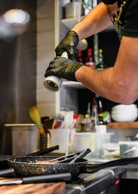 Cropped hands of man seasoning food in kitchen