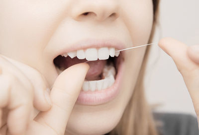 Midsection of woman cleaning teeth with string