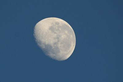 Low angle view of half moon against clear blue sky