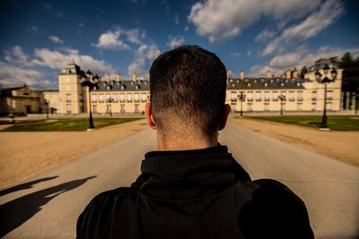 Rear view of man standing against buildings in city