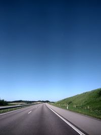 Empty road against clear blue sky