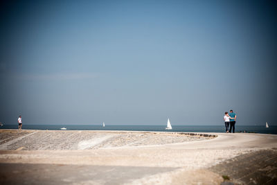 People standing on beach against sky