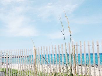 Wooden posts on beach against sky
