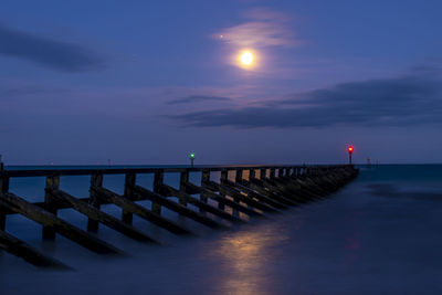 Pier over sea against sky during sunset