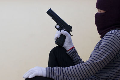 Side view of burglar holding handgun against wall