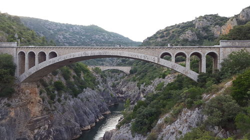 Arch bridge over mountain against sky