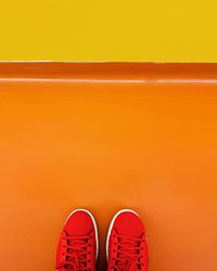 Red shoes on an orange floor with a yellow wall.