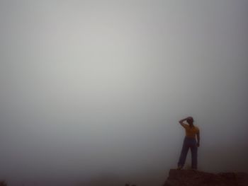 Man standing on rock against sky