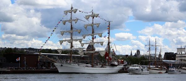 Boats moored at harbor against sky