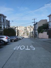 Cars on road by buildings in city against sky