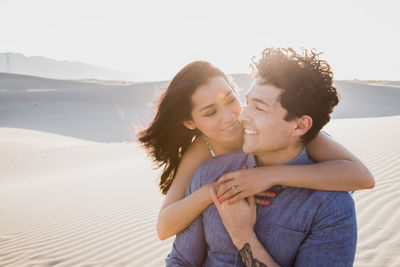 Smiling girlfriend embracing boyfriend at desert