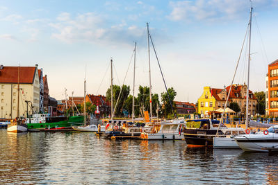 Boats moored at harbor against sky