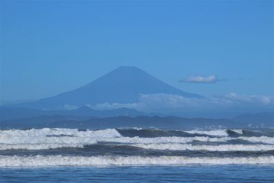 Scenic view of sea and mountains against clear blue sky