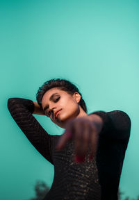 Portrait of young woman gesturing against clear sky