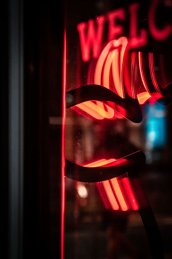 CLOSE-UP OF ILLUMINATED RED LIGHT AGAINST WINDOW