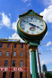 Low angle view of clock on pole against building