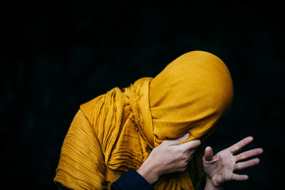 Midsection of man wearing scarf against black background