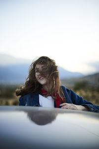 Young woman with tousled hair sitting in car