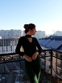 Woman standing by railing against buildings in city