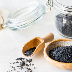 Black hawaiian rock salt in a jar, bowl and small wooden scoop.