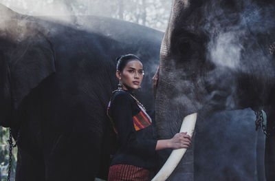 Young woman standing with elephant in temple