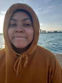 Close-up of young woman wearing hood against sky