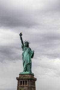 Low angle view of statue of liberty against cloudy sky