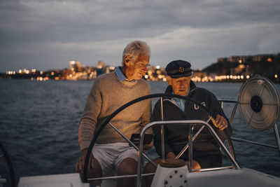 People sitting on boat sailing in sea against sky