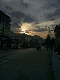 City street and buildings against sky at sunset