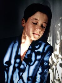 Close-up of girl with closed eyes standing against wall at home