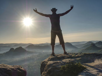 Rear view of man standing on rock against sky