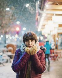 Portrait of woman standing in city during snowfall