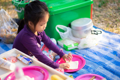 Cute girl eating while sitting on picnic blanket